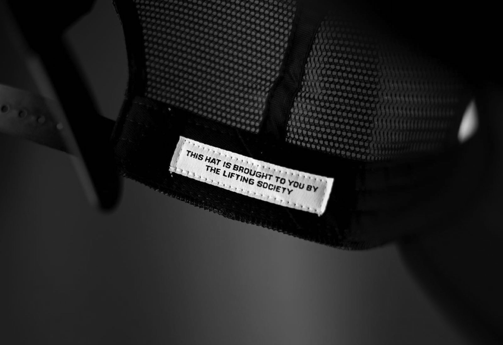 Inner label of a trucker hat reading 'This hat is brought to you by The Lifting Society.'