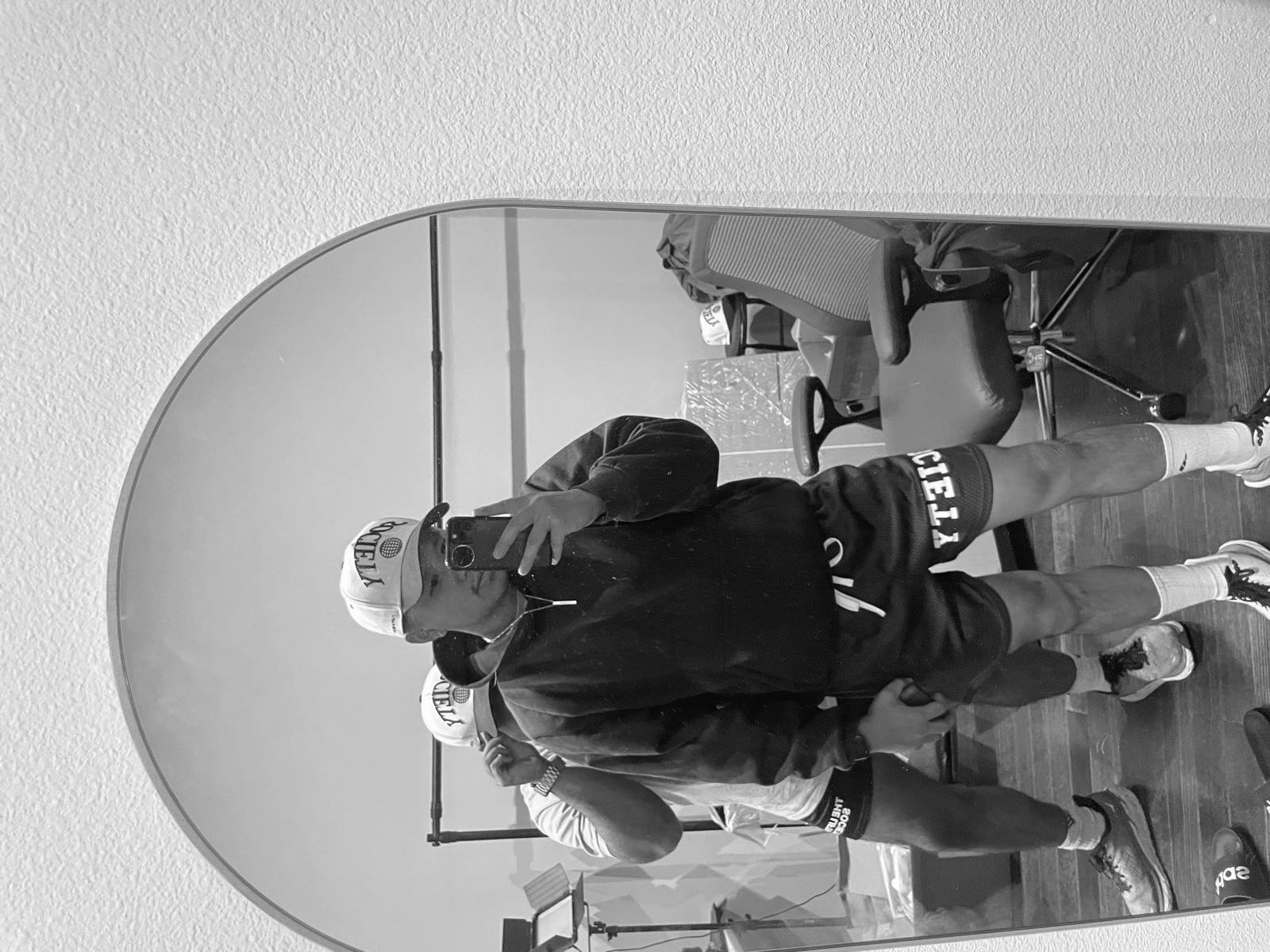 Mirror selfie wearing the Society trucker hat and Society mesh shorts.